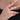 Side close-up view showcasing a hand wearing a gold ring with a bold black gemstone and a sparkling slim diamond band.